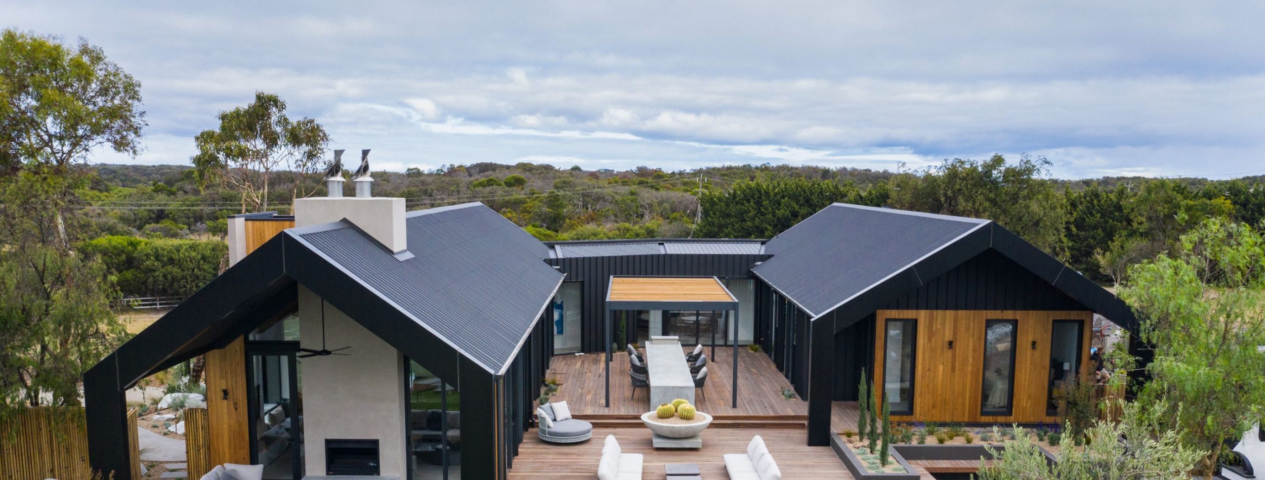 An Aerial View of a Modern House with Outdoor Furniture and Trees on the Other Side
